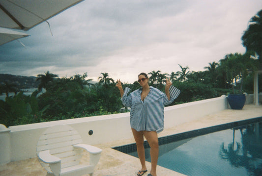 Ashley Graham standing by a pool with lush greenery in the background