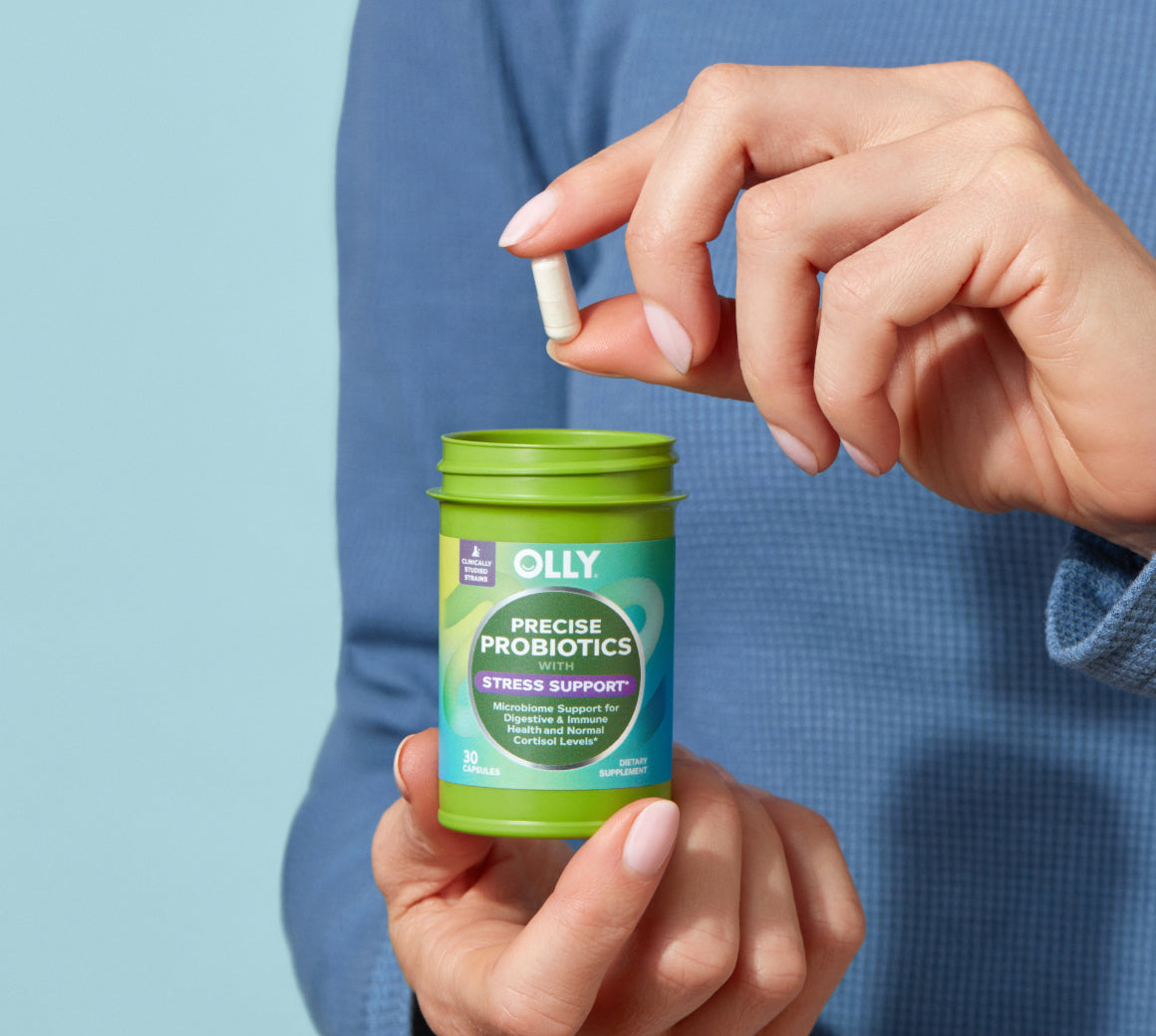 Woman holding OLLY Precise Probiotics bottle and capsule