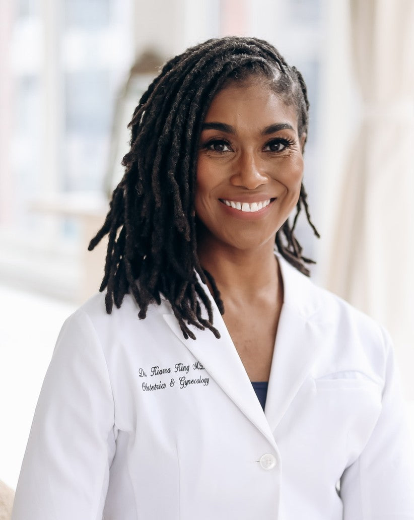 Dr. Kiarra King, M.D., FACOG, smiling in a white physician coat