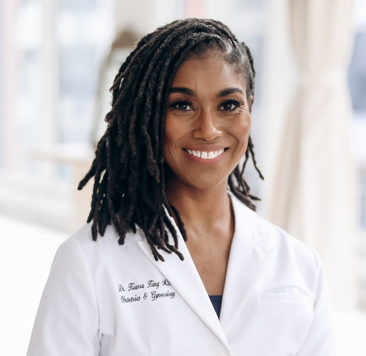 Dr. Kiarra King, M.D., FACOG, smiling in a white physician coat
